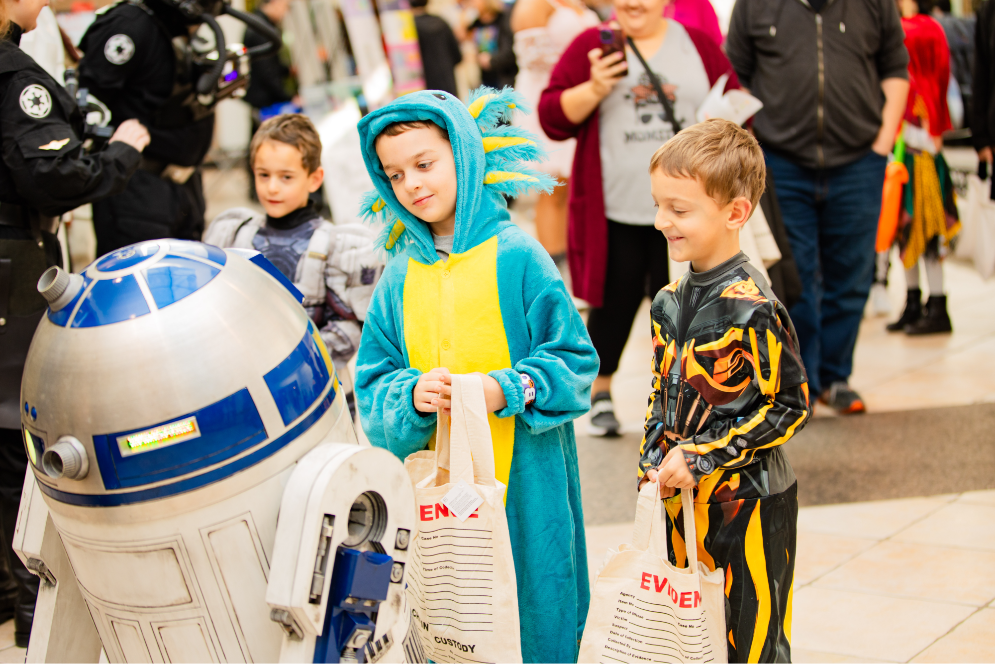 Three boys in halloween costumes talk to R2D2