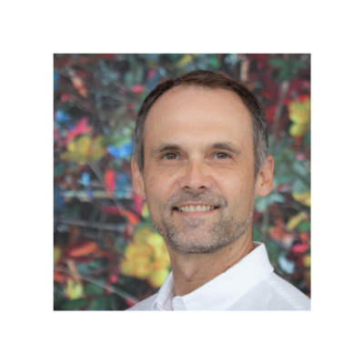 A picture of Matt Wyczalkowski in a white shirt with a colorful background.