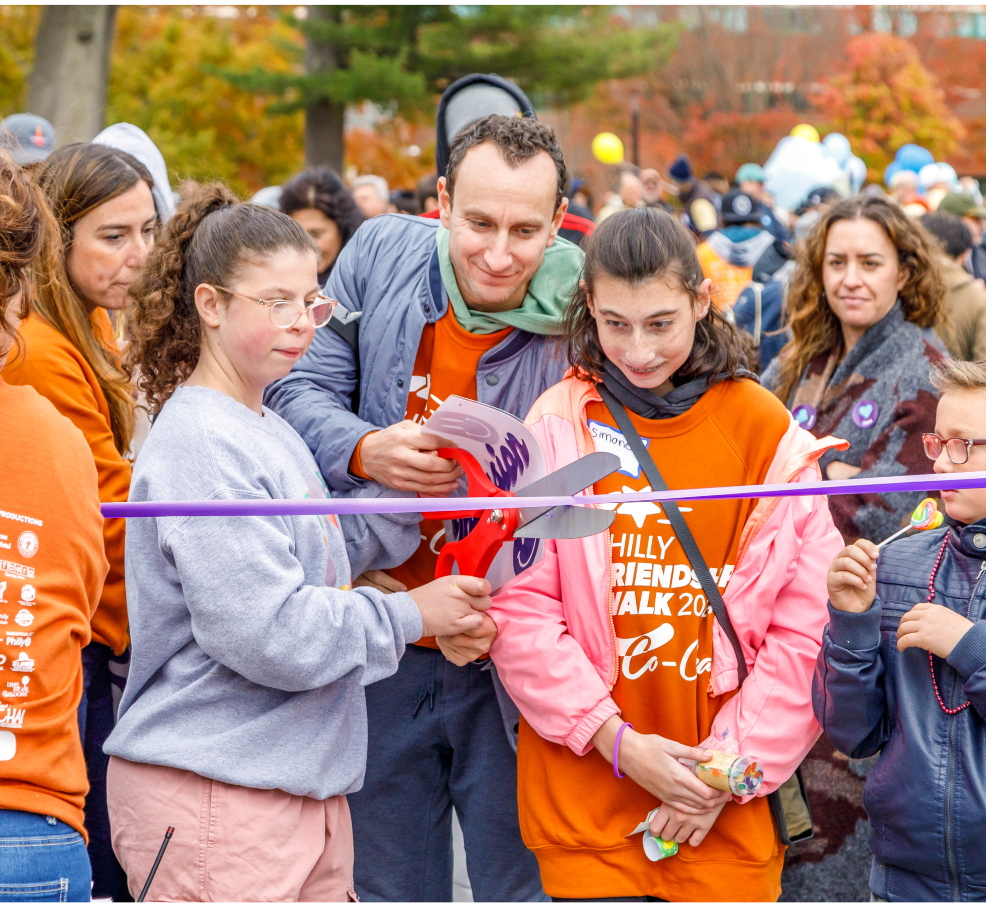 a crowd gathers at a starting line where a ribbon cutting is taking place