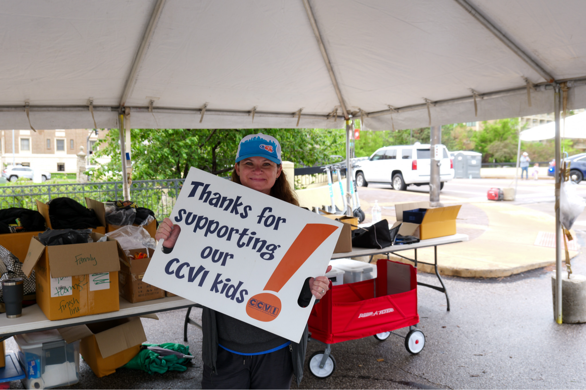 woman holding sign that says "thanks for supporting our ccvi kids!"