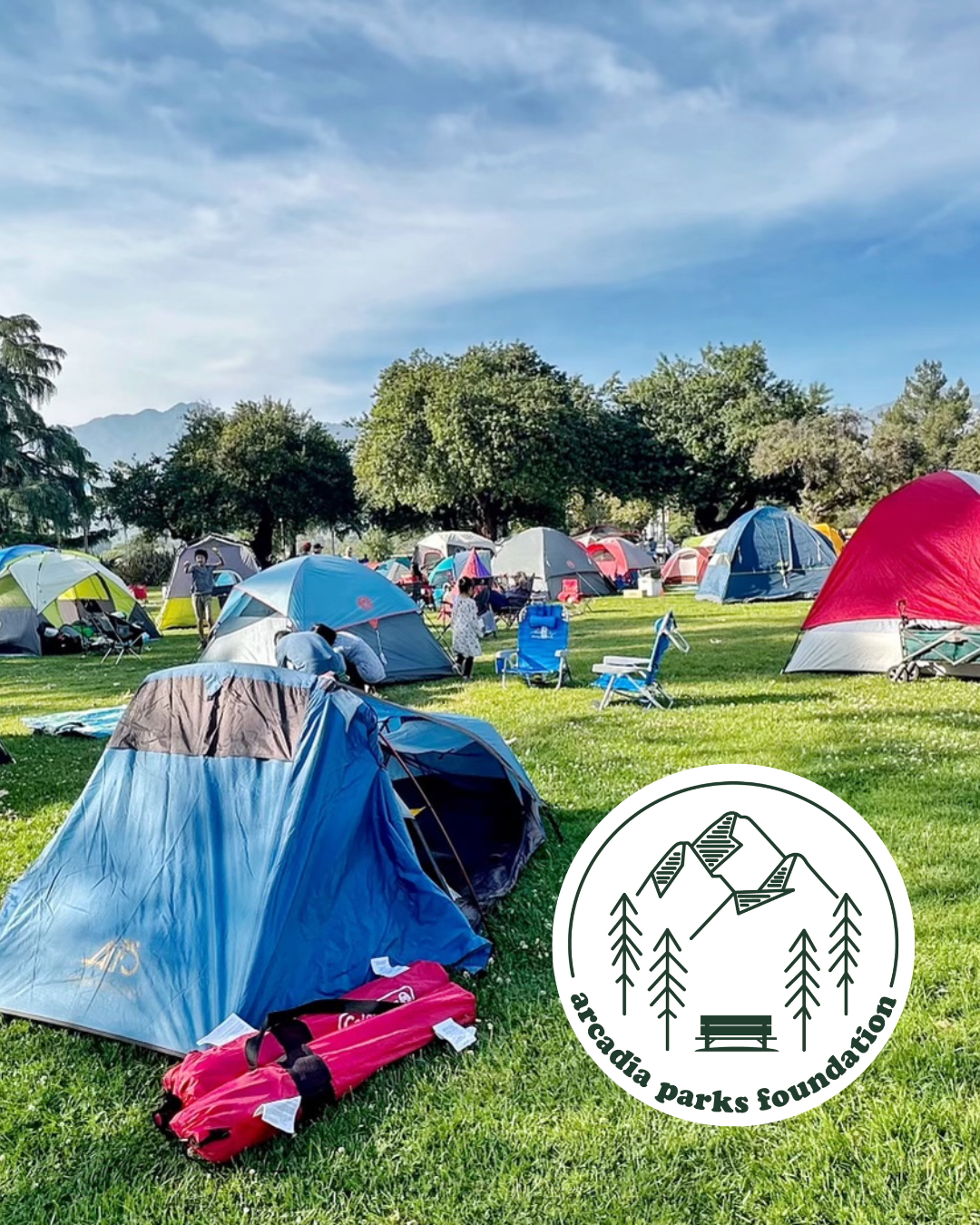 national campout promo photo showing lots of tents on green grass under a blue sky