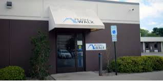 A picture of a beautiful brick school building with nice landscaping in front of it and a cloudy sky backdrop.
