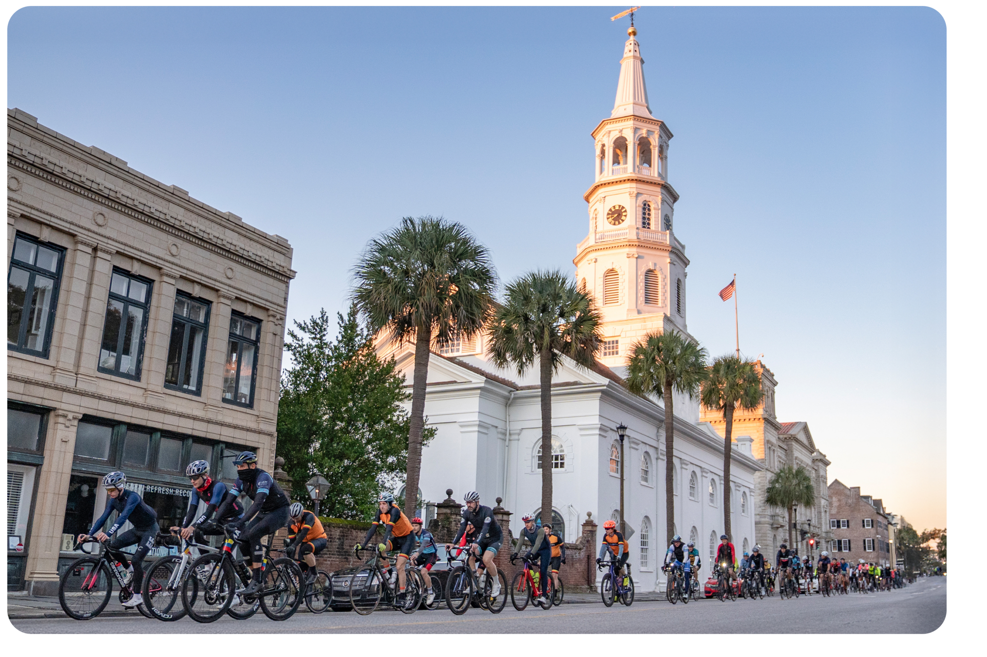 cyclists riding down Broad Street in Charleston, SC in front of St. Michaels's Church