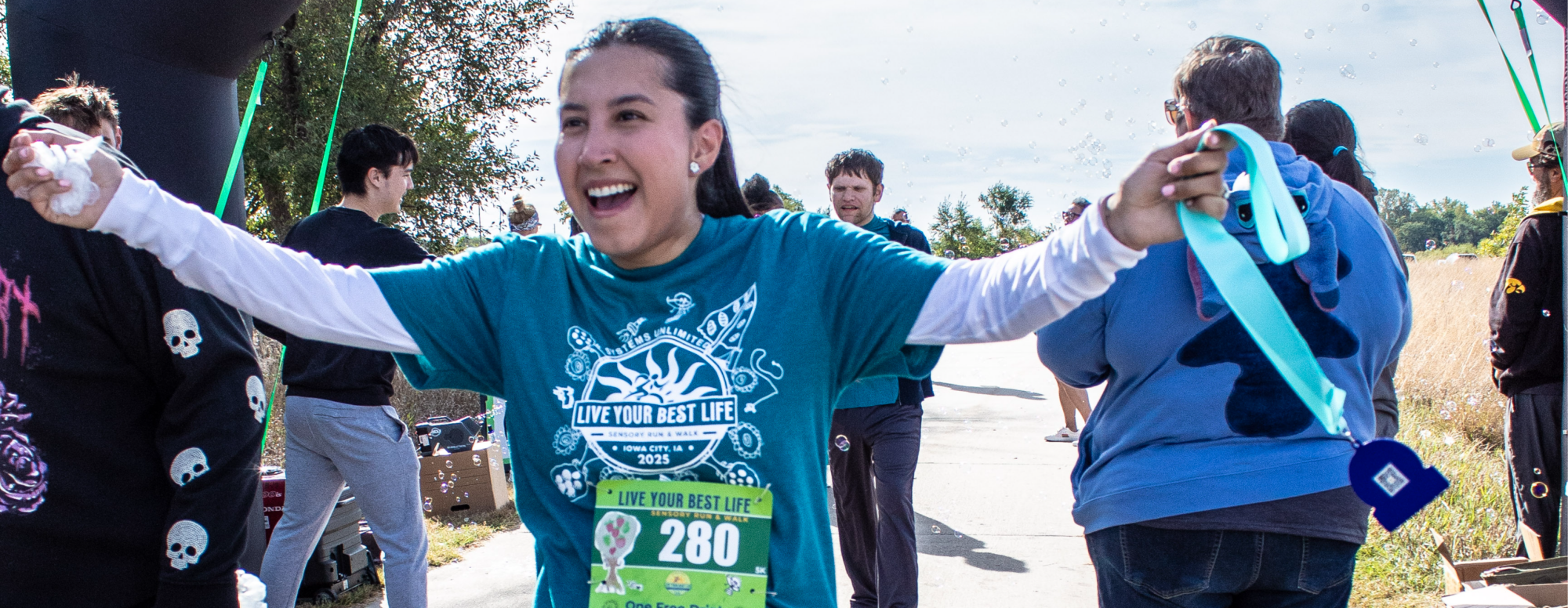Photo of a woman at the finish line of the Live Your Best Life Sensory Walk & 5K in Iowa City