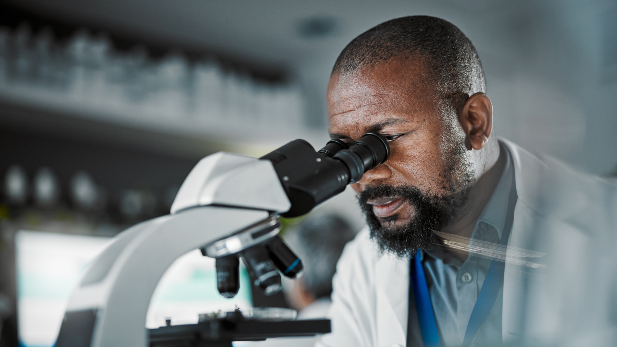 man in lab coat looking in microscope