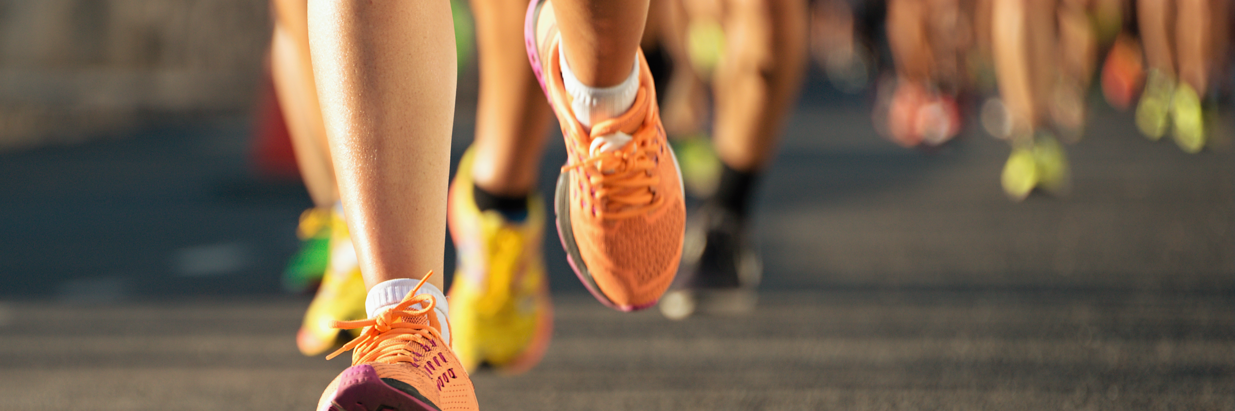 A closeup of runners' running shoes on pavement during the evening.