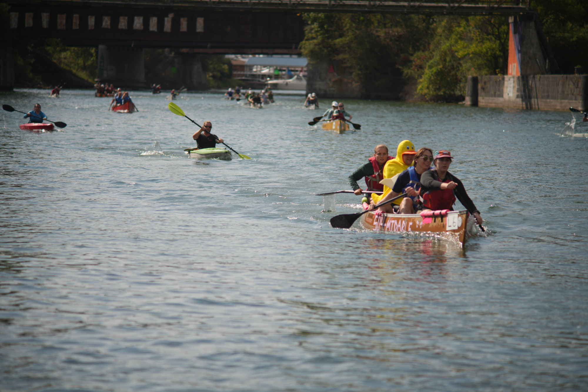 4 person canoe with kayaks and canoes in pursuit on the canal