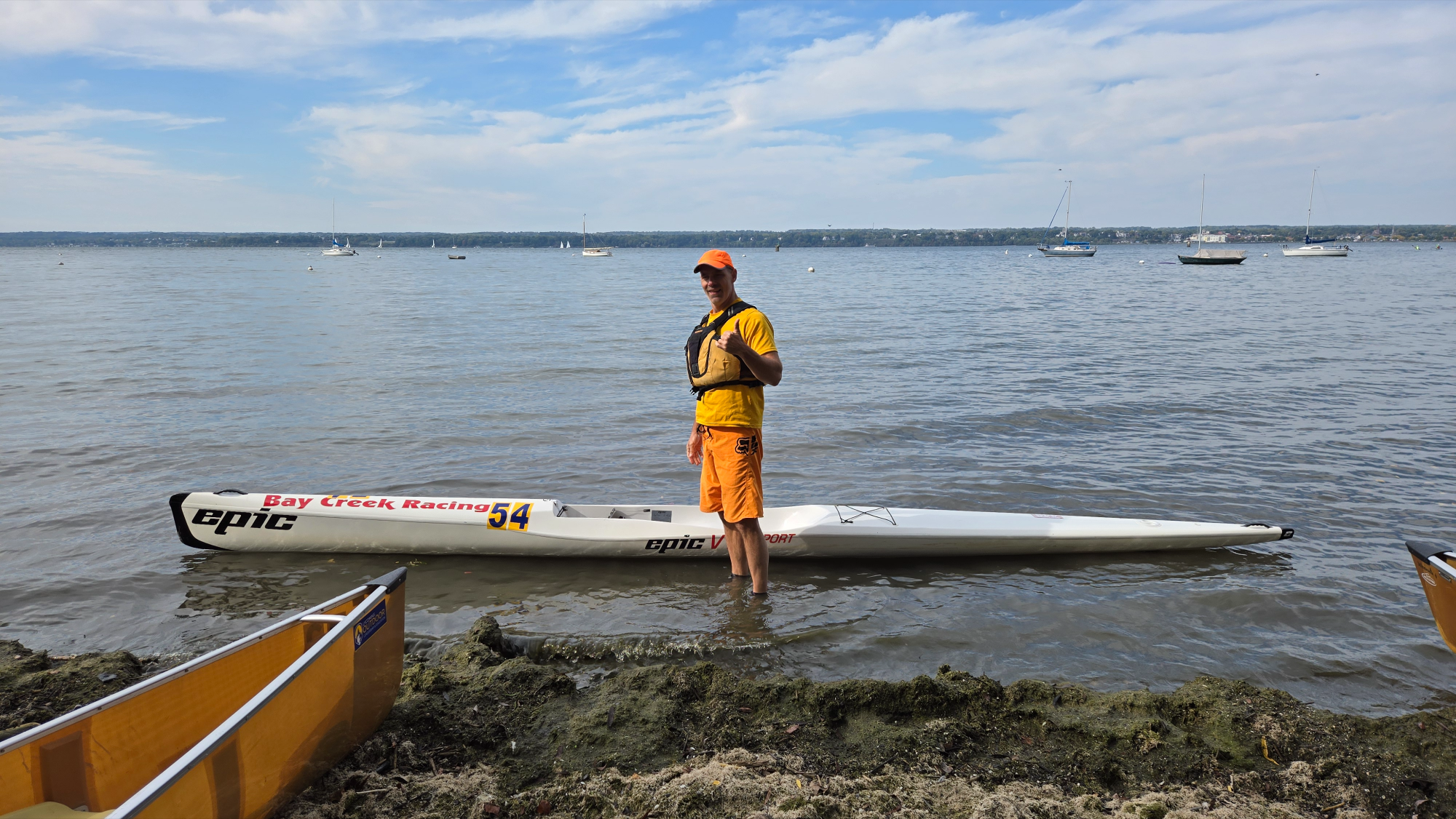 epic surfski with paddler 54 standing near shore