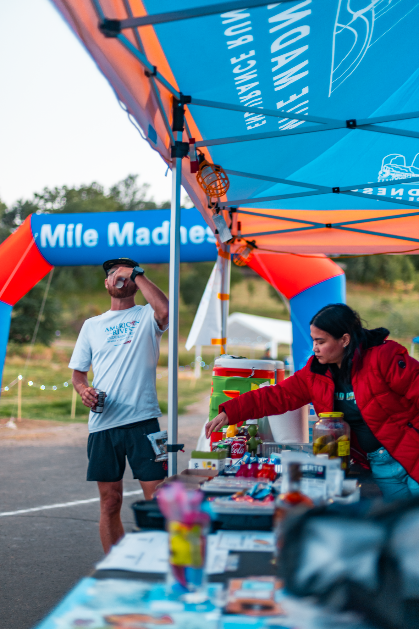 Volunteer refilling food while runner drinks water from cup