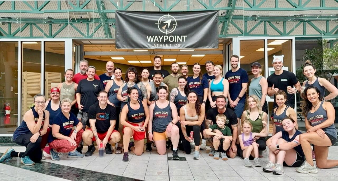 Waypoint Athletics athletes gathered beneath the gym banner after a community workout.