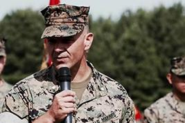 Col. Kyle Phillips speaking into a microphone in Marine Corps uniform