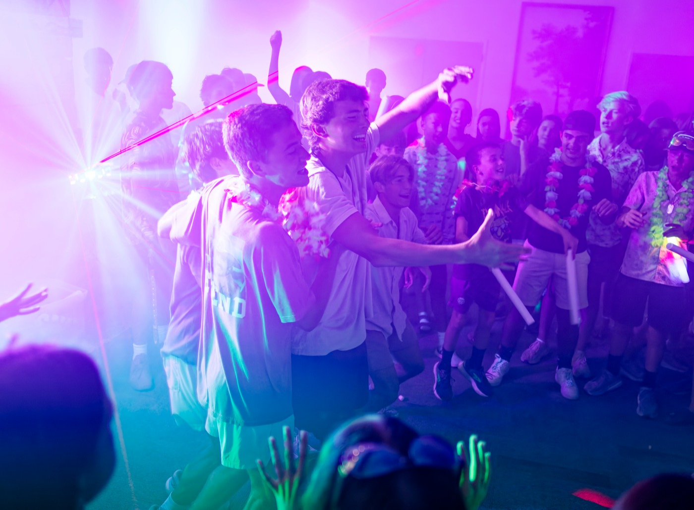 Campers dancing together under colorful lights at the annual themed camp dance