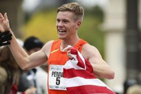 Tyler Pennel celebrating a marathon finish with an American flag