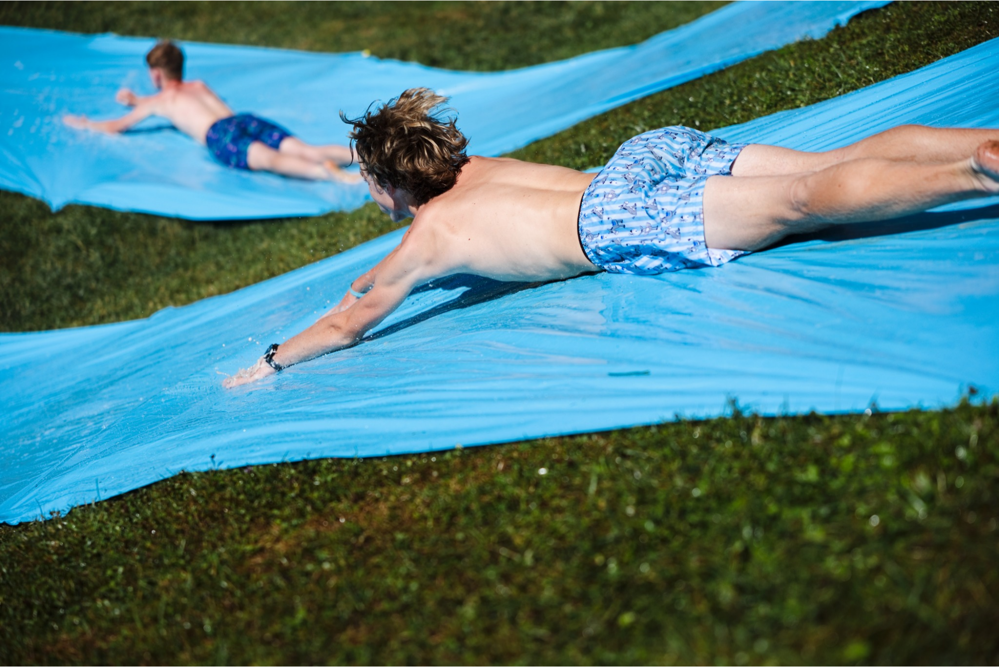 Campers racing side by side during the Slip and Slide Relay