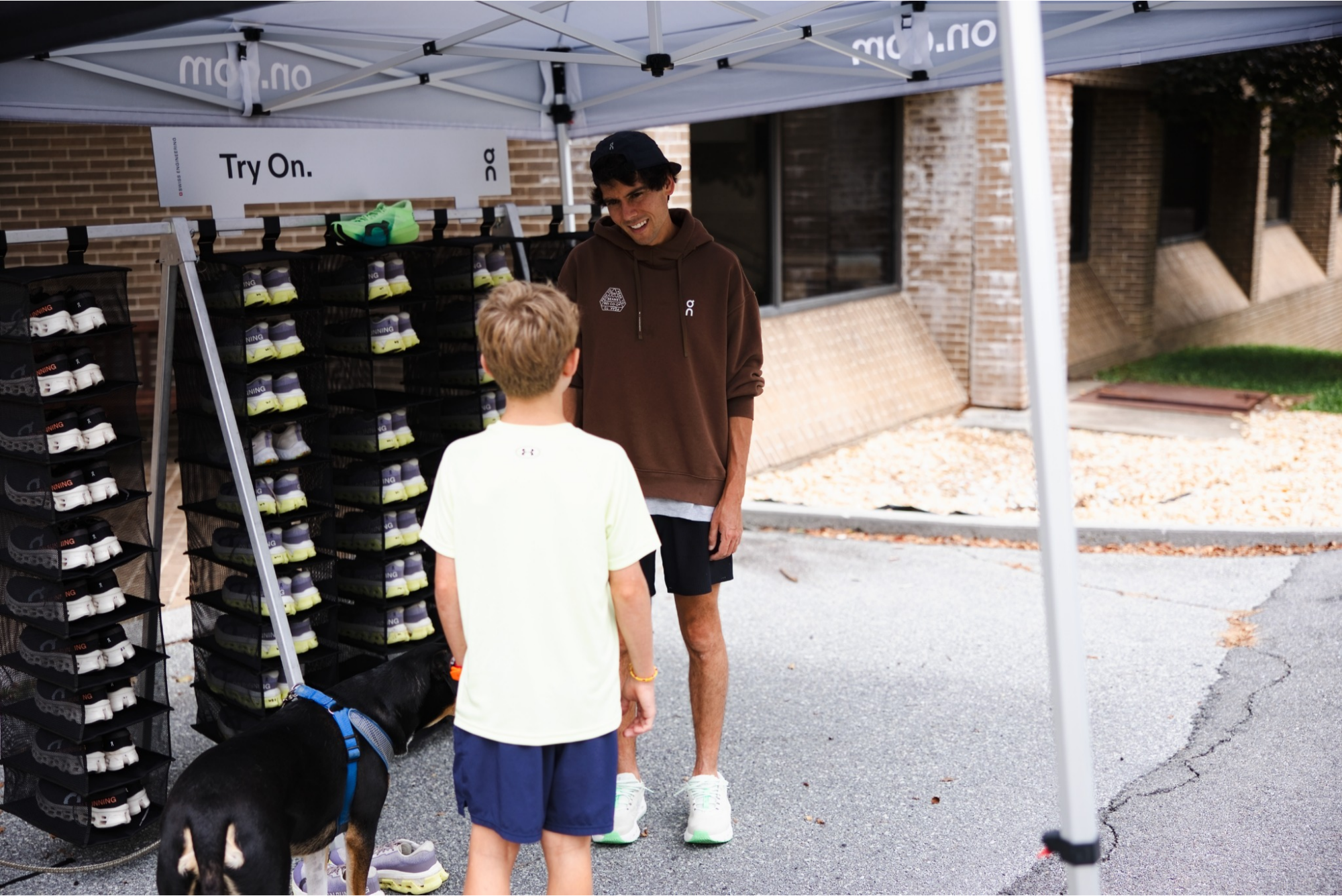 An On representative talks with a camper beside running shoe displays
